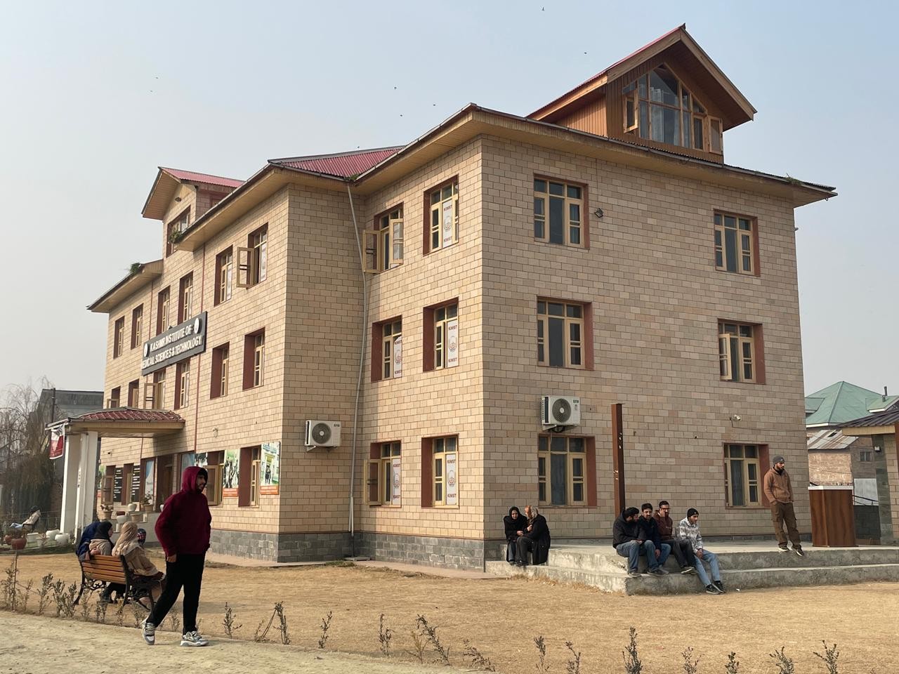 Students sitting on the steps and walking in the grounds outside the Kashmir Institute of Medical Sciences & Technology building