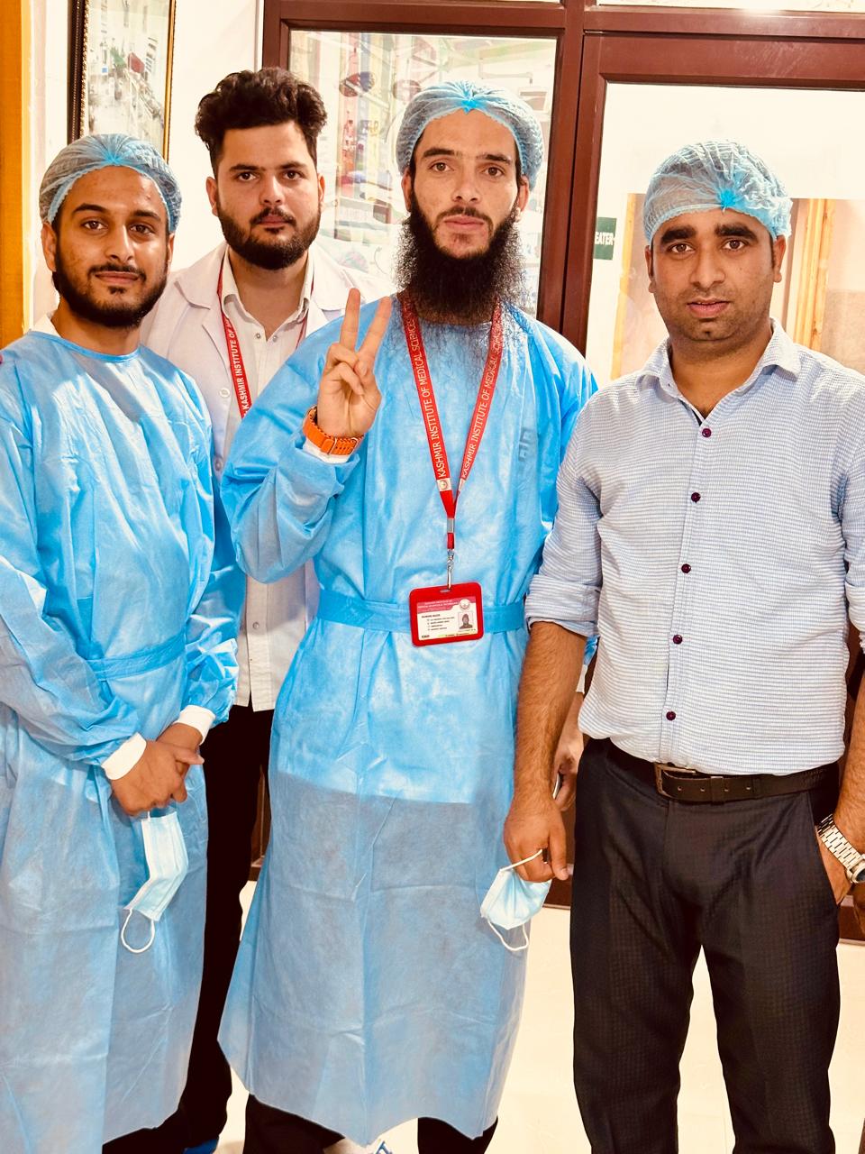 KIMST students in surgical gowns and caps wearing red ID lanyards